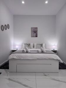 a white bedroom with a large bed and two tables at Casa Elia AXD in Alexandroupoli +26 photos