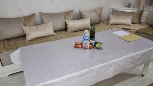 ein weißer Tisch mit einer Flasche Wasser und einer Flasche in der Unterkunft Mini villa trougout in Al Hoceïma