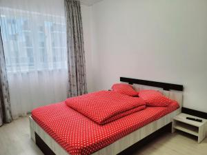 a bedroom with a bed with red pillows and a window at Double rooms apartament in Sînpetru
