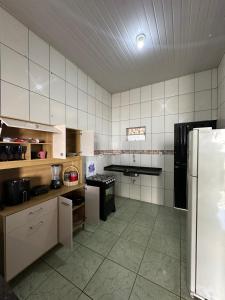 a kitchen with white tiled walls and a refrigerator at Apto garagem incluso in Marabá