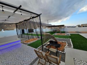 een schommel op een terras met twee stoelen bij Sinkhole Chalet in Bimmah