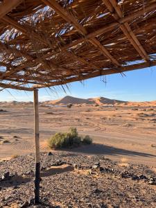 une vue du désert avec un toit de chaume dans l'établissement Travel Oasis Merzouga Camp, à Merzouga