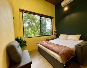 een slaapkamer met een bed, een raam en een stoel bij Jungle House with Private Jacuzzi in Uvita