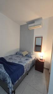 ein Schlafzimmer mit einem Bett, einem Spiegel und einem Nachttisch in der Unterkunft Aurora Peruíbe Hotel in Peruíbe