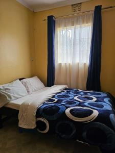 a bed sitting in a room with a window at ZuriStay in Nakuru