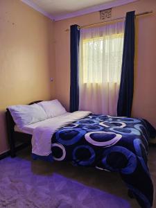 a bedroom with a bed and a window with curtains at ZuriStay in Nakuru