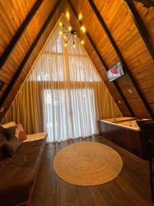 een woonkamer met een bank en een groot raam bij Chalé Riacho - Cabana em Contenda - Chalé romântico com hidromassagem in Contenda