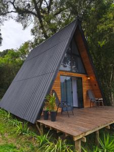 een kleine hut met een zwart dak op een houten terras bij Chalé Riacho - Cabana em Contenda - Chalé romântico com hidromassagem in Contenda