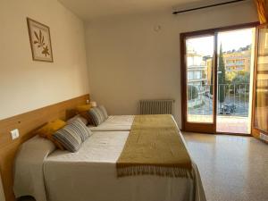 a bedroom with a large bed and a large window at Apartamentos El Sol in Tossa de Mar