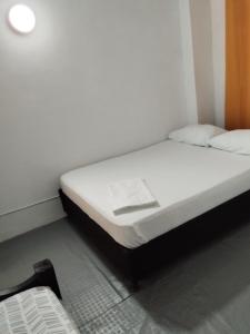 un letto in una camera con lenzuola e cuscini bianchi di Hostal Paloma Café a Palomino