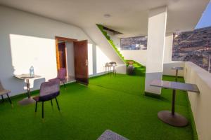 Zimmer mit grünem Teppich, Stühlen und einem Tisch in der Unterkunft Mountain Echo Inn in Taiyiba