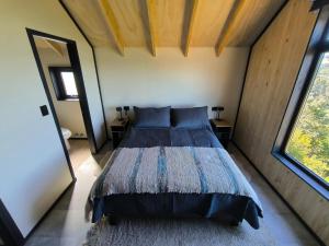 a bedroom with a bed in a room with windows at Casa Esquila de Chiloé in Chonchi