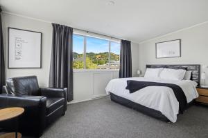 een slaapkamer met een bed, een stoel en een raam bij The Upper Rooms in Nelson