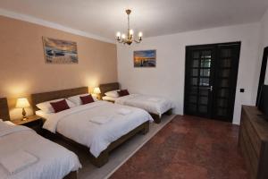 une chambre avec deux lits et un lustre dans l'établissement Ambient Deluxe Apartman, à Gyula