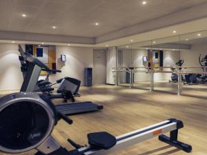 a gym with treadmills and ellipticals in a room at Mercure Maurepas Saint Quentin in Maurepas