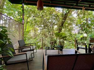 een patio met stoelen, tafels en bomen bij Jungle House with Private Jacuzzi in Uvita