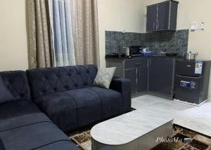 a living room with a blue couch and a kitchen at Nova apartments in Amdalai