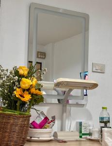 un bagno con specchio e fiori su un bancone di เอินอพาร์ตเมนต์ a Ban Phae Buak Ha