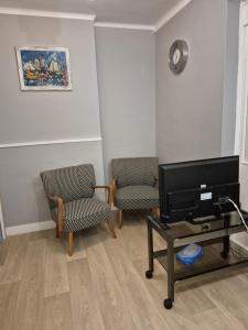 een woonkamer met 2 stoelen en een flatscreen-tv bij Le break en nord Cotentin in Cherbourg en Cotentin