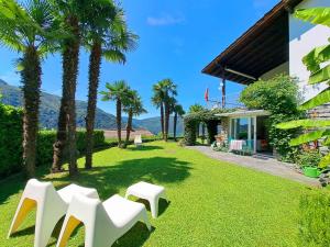 a yard with white chairs and palm trees at Casa Bellavista Rovio in Rovio