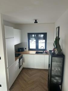 a kitchen with white cabinets and a sink and a window at BeskidView Meszna 1 in Meszna