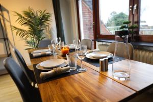 a wooden table with plates and glasses on it at Nalia Homes - Elegant Central Apartment in Pinneberg