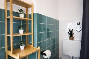 a bathroom with green tiled walls and shelves with potted plants at Nalia Homes - Elegant Central Apartment in Pinneberg +20 photos