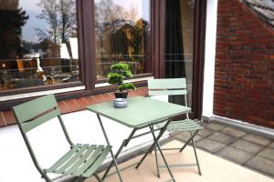 a table and two chairs on a porch with a potted plant at Nalia Homes - Elegant Central Apartment in Pinneberg