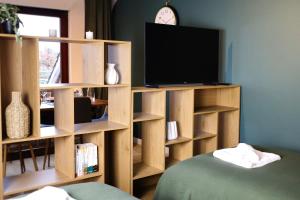 a living room with a tv and wooden book shelves at Nalia Homes - Elegant Central Apartment in Pinneberg