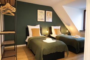 two beds in a room with green walls at Nalia Homes - Elegant Central Apartment in Pinneberg