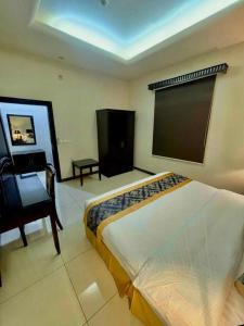 a bedroom with a bed and a chair and a large screen at Quiet Rooms 8 Serviced Apartments in Riyadh