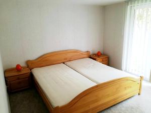 een slaapkamer met een houten bed, twee ladekasten en een raam bij Ranchhaus in Baumannsberg