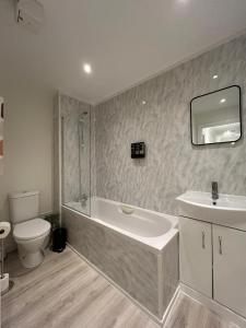 a bathroom with a tub and a sink and a toilet at Modern 2 Bed Apartment, Secure Parking, Central in Hemel Hempstead
