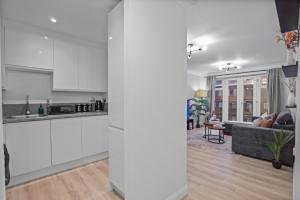 an open kitchen and living room with white cabinets at Modern 2 Bed Apartment, Secure Parking, Central in Hemel Hempstead