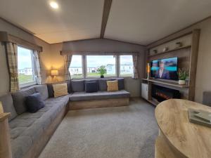 a living room with a couch and a tv at Silversands - Private Caravan Let in Lossiemouth
