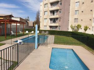 a swimming pool with a fence next to a building at Arriendo Departamento Diario en Copiapo in Copiapó