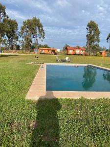 a person standing in the grass next to a swimming pool at Cabaña Palmas de Tunquen in Tunquén