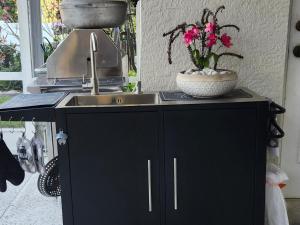 een aanrecht met een wastafel en een vaas met bloemen bij Ocean Spa Retreat in Port Saint Lucie