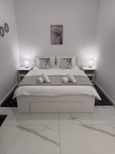 a white bedroom with a large bed with two tables at Casa Elia AXD in Alexandroupoli