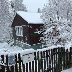 a house covered in snow next to a fence at Páfrány - Lak in Mátraszentimre