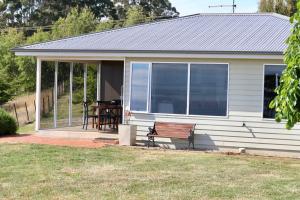 a small white house with a bench and a table at Penguin Seaside Farm in Penguin