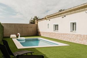 a backyard with a pool and a swan on the grass at Villa alegre in Elche
