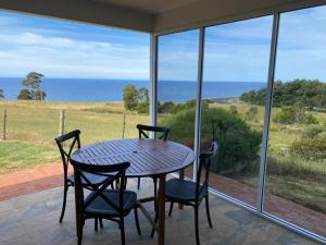 a table and chairs on a porch with a view of the ocean at Penguin Seaside Farm in Penguin