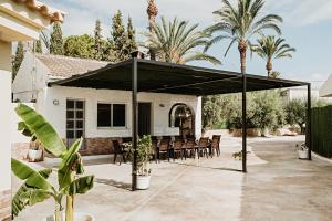 a pavilion with tables and chairs in front of a house at Villa alegre in Elche