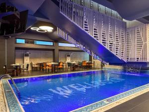 a large swimming pool in a hotel with tables and chairs at Wellborn Hotel Limited in Lekki