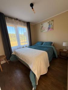 een slaapkamer met een bed en een groot raam bij Acogedora Casa Los Canelos in Puerto Varas