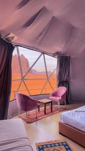 a room with beds and chairs and a large window at RUM NADINE LUXURY CAMP & Bubbles Hotel in Wadi Rum