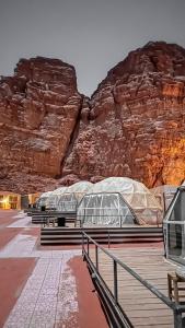 a group of benches on a boardwalk in front of a mountain at RUM NADINE LUXURY CAMP & Bubbles Hotel in Wadi Rum +40 photos