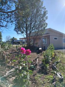 a house with a pink flower in the yard at Cabaña 3 Aeropuerto el Tepual in Puerto Montt