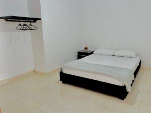 een witte slaapkamer met een bed en een tafel bij Los Nonos Hostel in Guadalupe